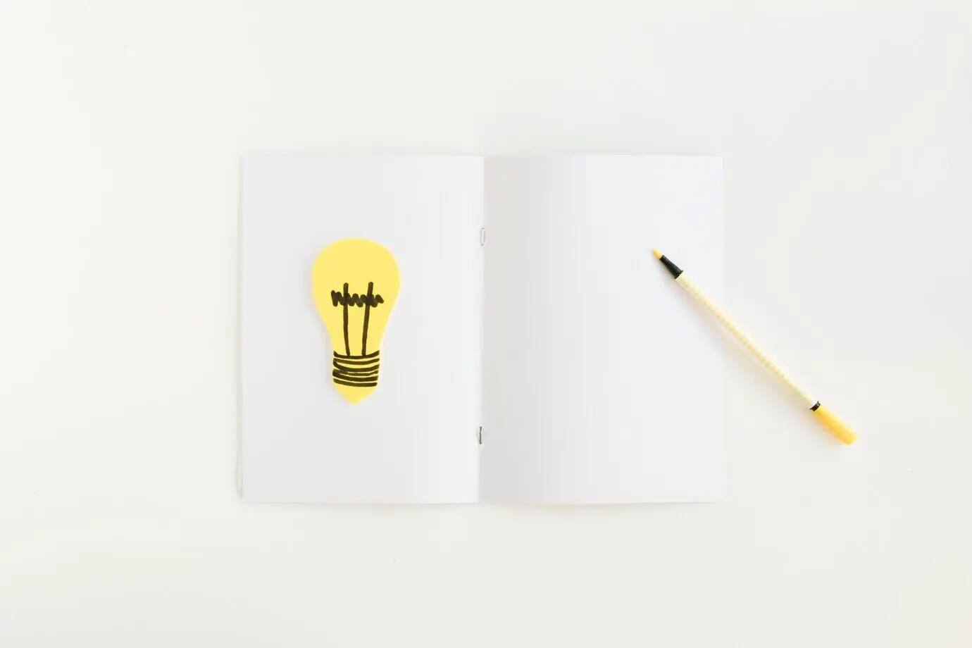 Blick von oben auf einen Stift und eine Glühbirne, die auf einer Karte liegen.