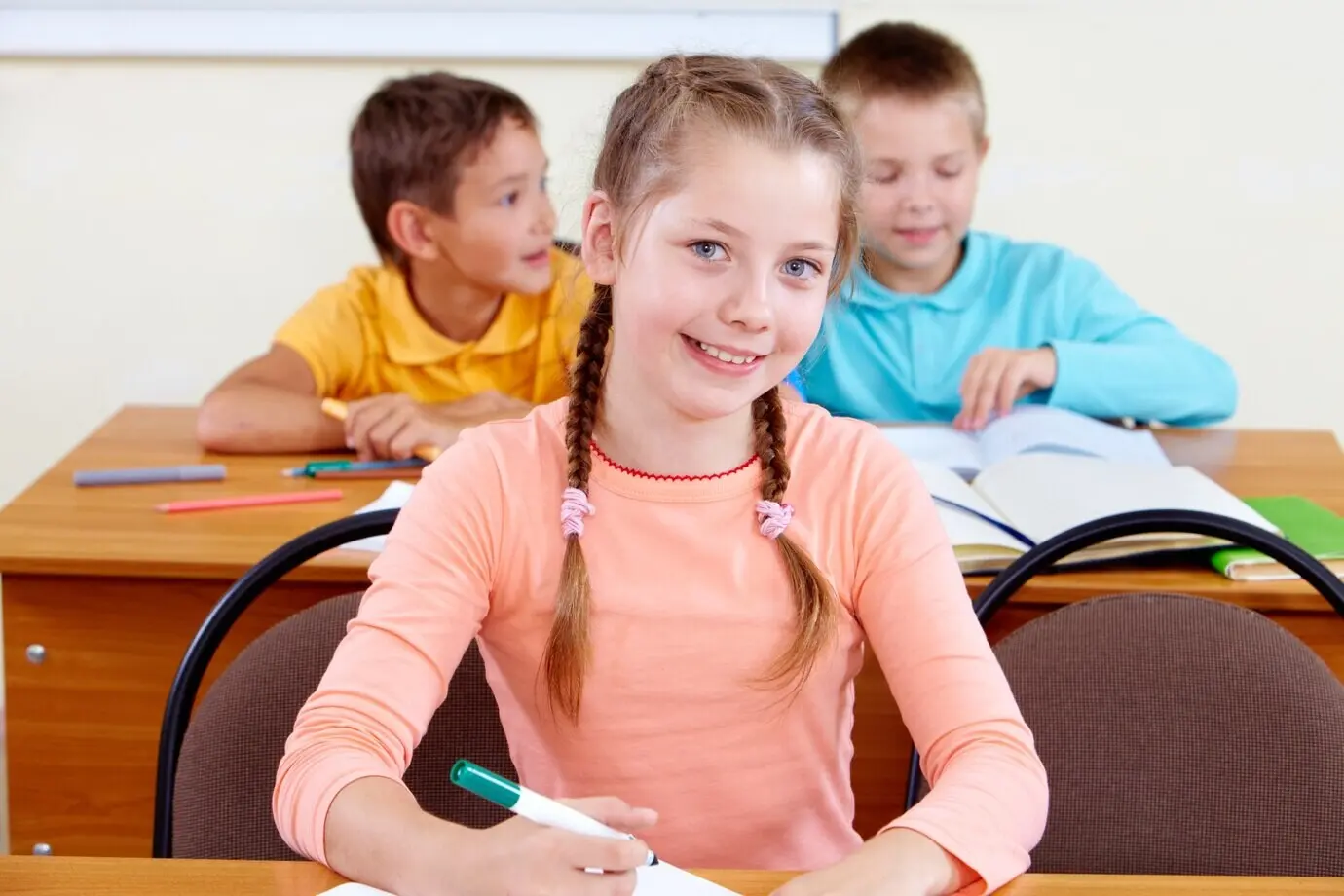 Lächelndes Mädchen mit Mitschülern im Hintergrund.